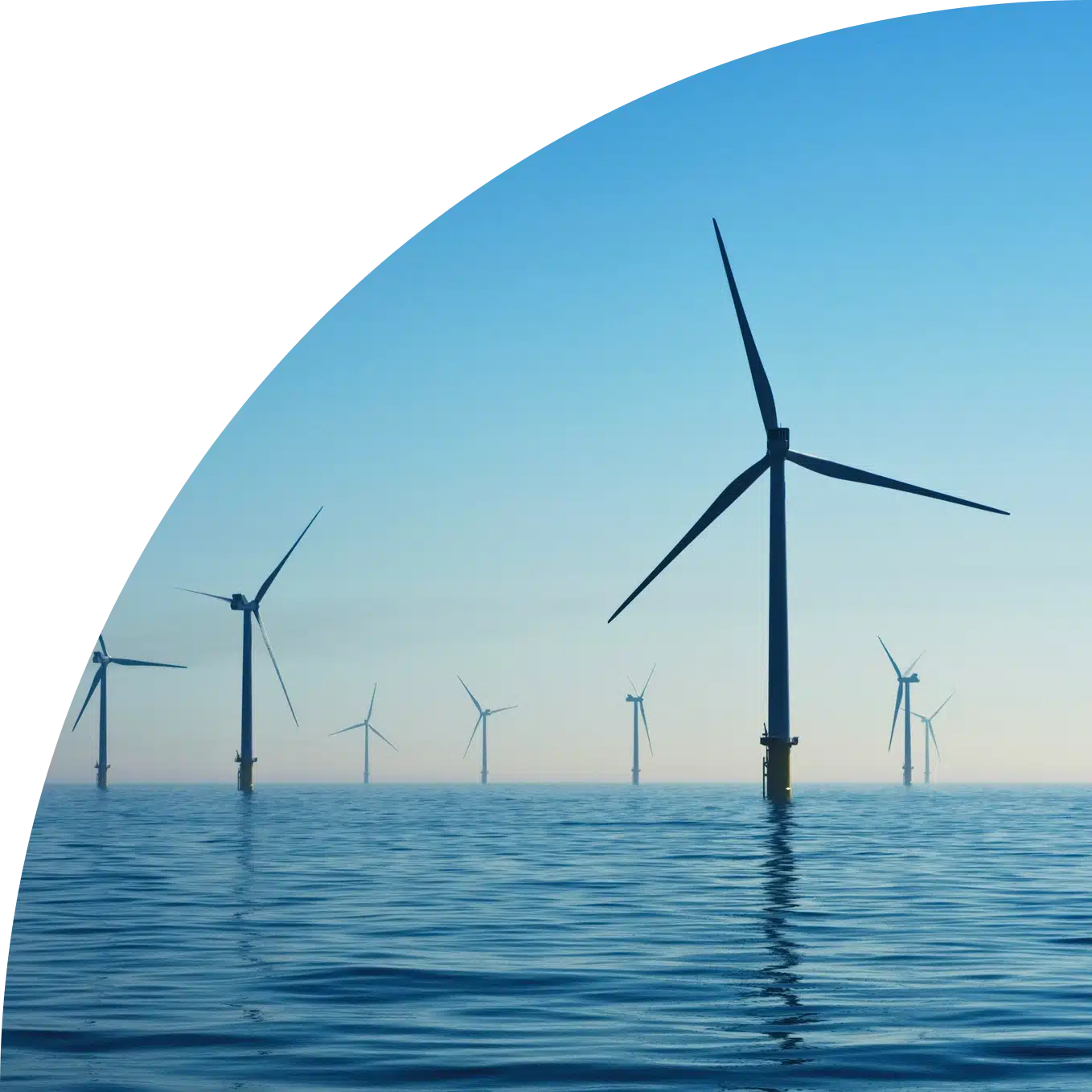 Multiple offshore wind turbines silhouetted against clear blue sky and calm ocean water, arranged in rows across the seascape with reflections visible on the water surface, presented in a circular frame design