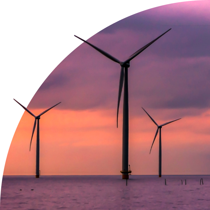 Three offshore wind turbines in the sea at sunset with purple and orange sky