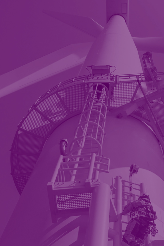 Technician in safety gear climbing maintenance ladder on offshore wind turbine tower with turbine blades in background